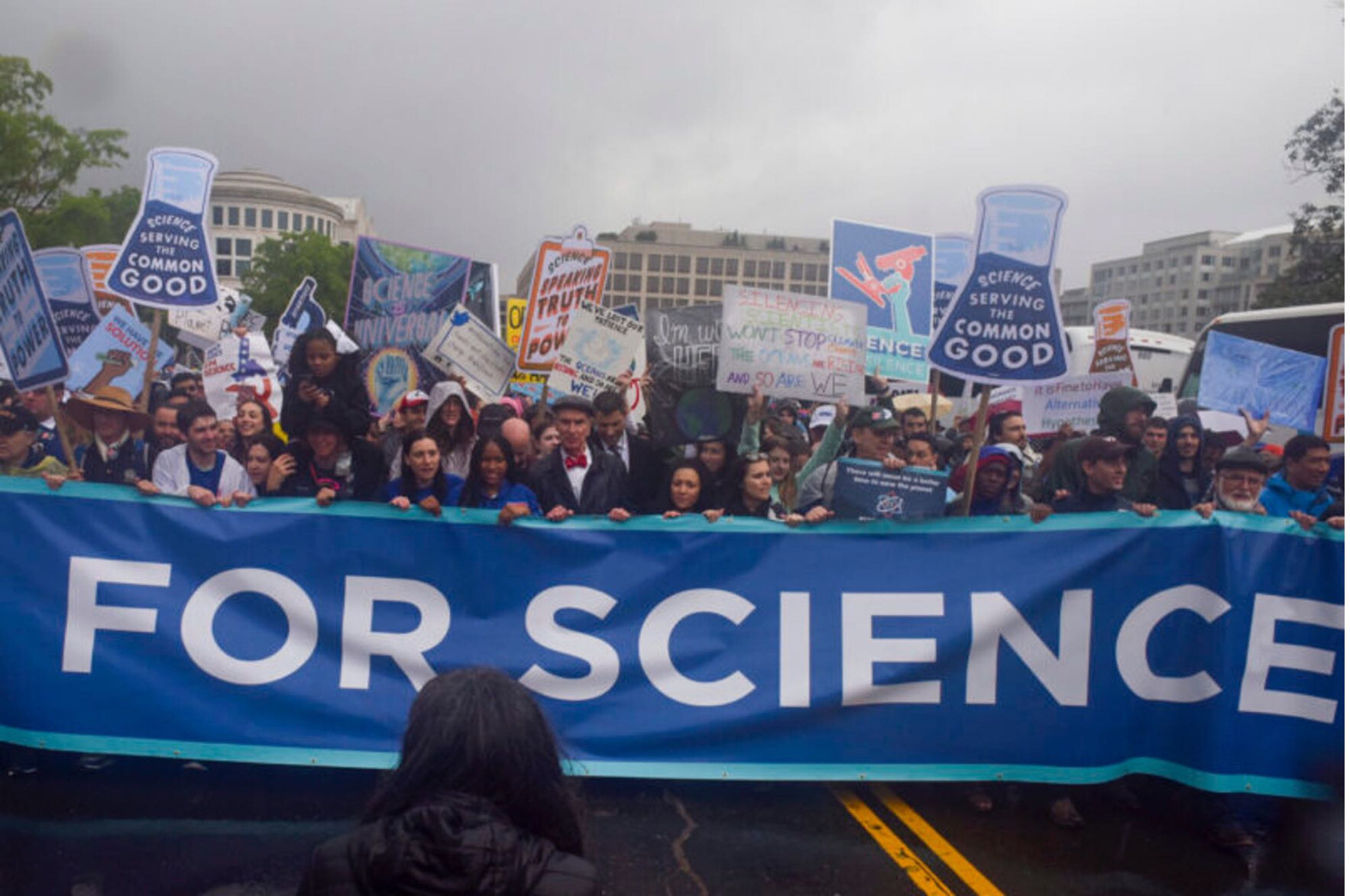 Photo of scientists protesting with banner reading "For Science".
