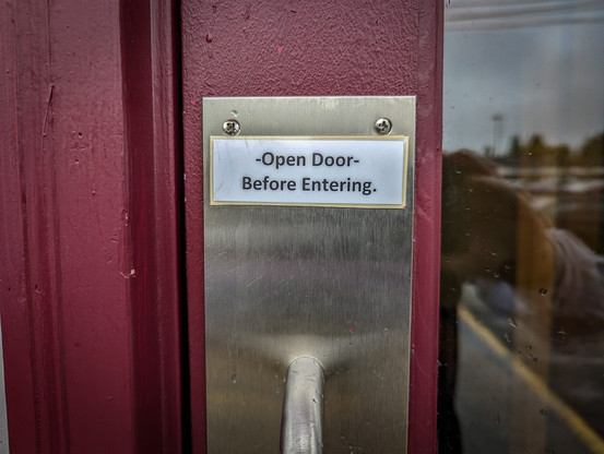 Sign on door to restaurant "Open Door Before Entering"