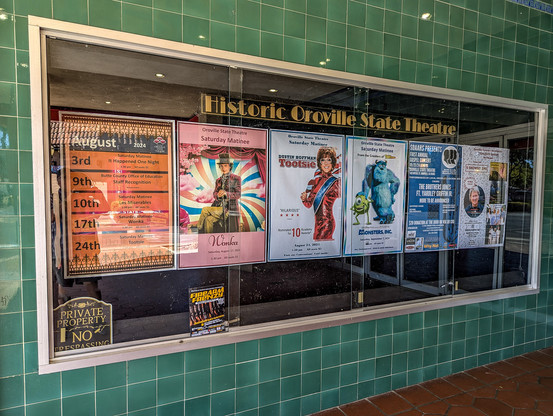 The Oroville State Theater - window with posters of coming attractions. 

https://www.orovillestatetheatre.com/

Built between 1927 and 1928, the State Theatre was designed by San Francisco architect Timothy Pflueger and opened its doors on April 7, 1928. It was one of several movie palaces owned and operated by the T&D chain throughout California, a number of which Pflueger designed for the company. The State Theatre was Oroville’s first Spanish Colonial Revival style building, one of only two high examples of the style in the city.

This style of architecture is growing increasingly rare in California. It was originally popular in California and Florida, but with a massive influx of population and the resulting implications to development, many of the original buildings in California were torn down to make way for new construction. Most of the remaining examples are tucked away in smaller communities where development has occurred at a slower rate and older buildings were left mostly intact. The Oroville State Theatre is one such example, but it is also an example of how limited small town resources make restoration and preservation difficult. It is vital that these communities make every effort to save, salvage, and protect these remaining structures.

